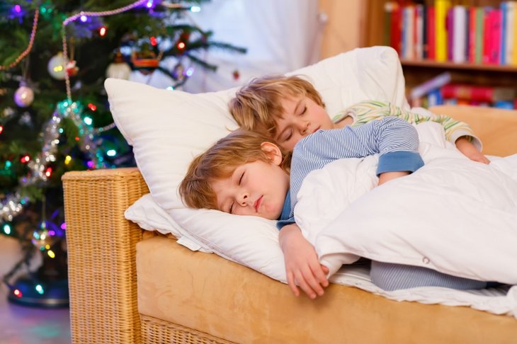 Sovende børn foran juletræ